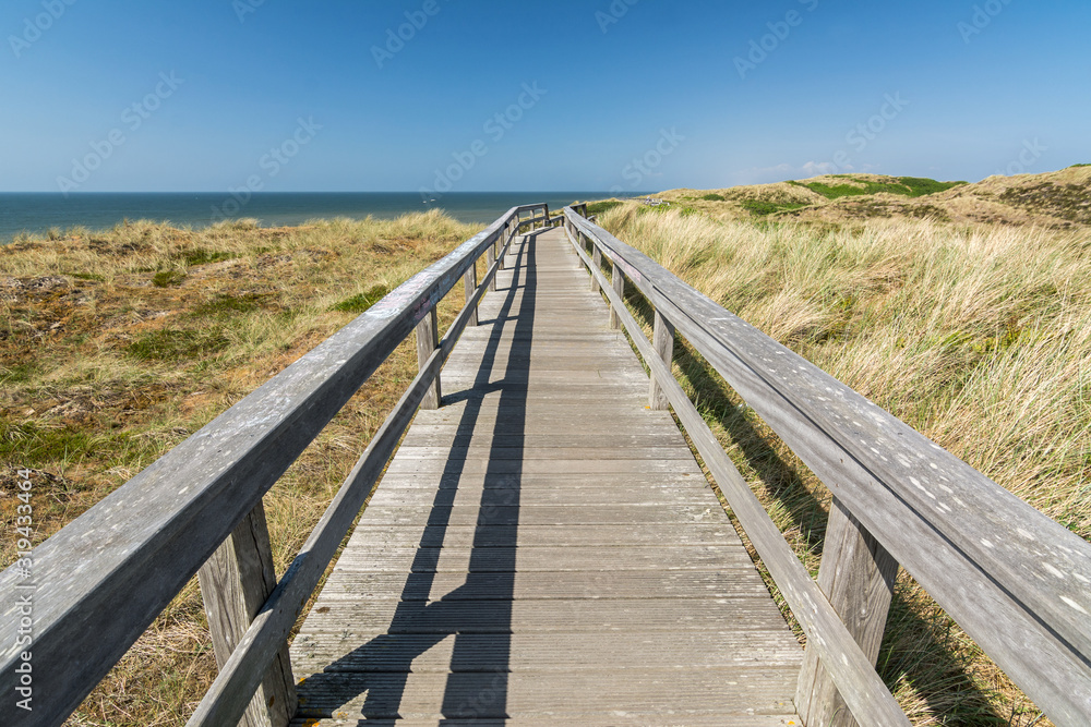Wooden footpath through the dunes leading towards the ocean on the island of Sylt in Northern Germany