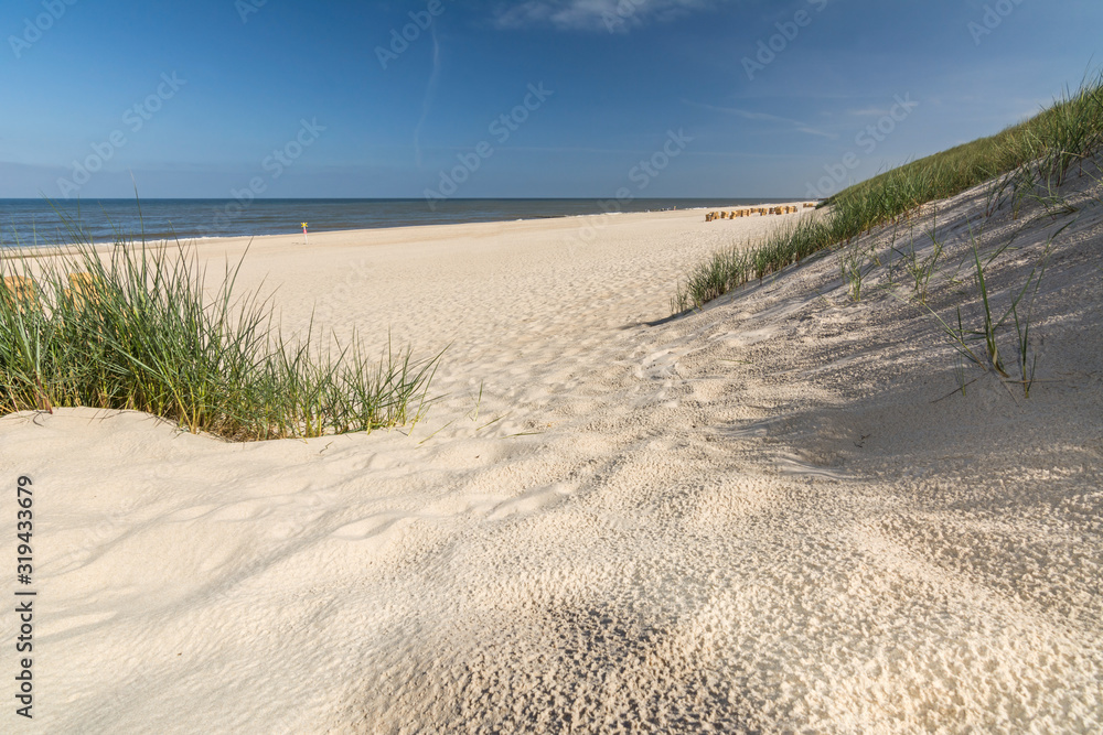 Looking onto a beautiful beach through the dunes and beach grass on the island of Sylt in Northern Germany Looking onto a beautiful beach through the dunes and beach grass on the island of Sylt in Northern Germany