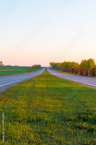 sunrise dawn over a rural meadow field and country driving road. Countryside landscape sun over horizon dawn behind the city copy space