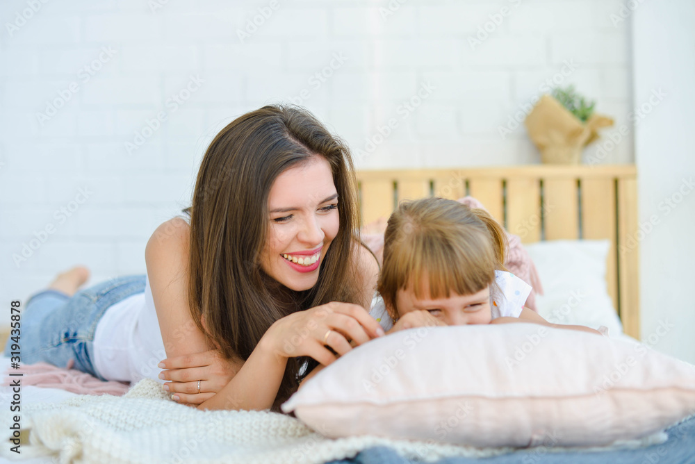 mom and daughter are lying in bed and laughing mom and daughter are lying in bed and laughing
