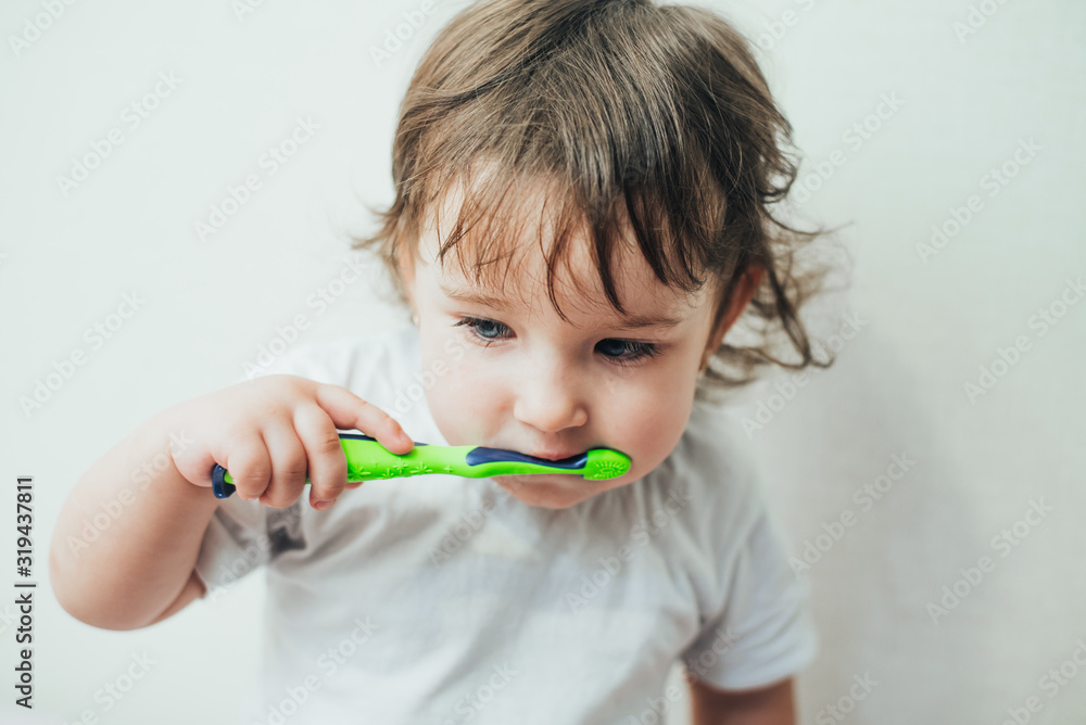 Little girl brushes her teeth with a toothbrush on a light background Little girl brushes her teeth with a toothbrush on a light background
