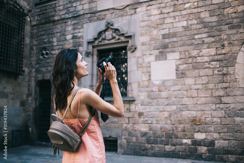 Pensive adult woman shooting with camera in old town Pensive adult woman shooting with camera in old town