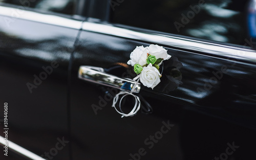 Beautiful decoration of a wedding black car. Door, handle and white flowers of roses.