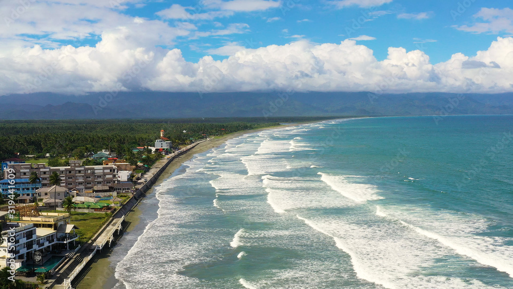 Sandy beach and ocean waves, aerial view. Coastline with hotels and tourists. Surfers in the water. Sabang Beach, Baler, Aurora, Philippines. Summer and travel vacation concept. Sandy beach and ocean waves, aerial view. Coastline with hotels and tourists. Surfers in the water. Sabang Beach, Baler, Aurora, Philippines. Summer and travel vacation concept.