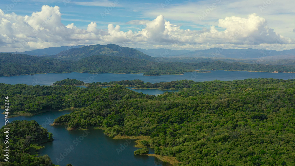 Clouds over a blue lake among green hills and mountains covered with rainforest. Aerial view: Pantabangan Lake. Philippines, Luzon.