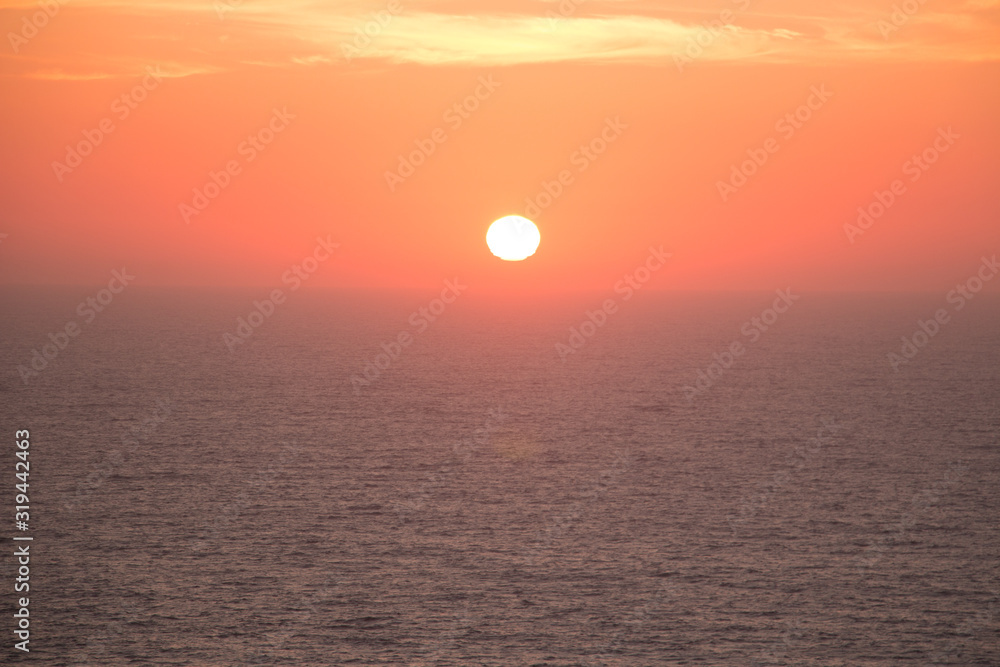 Sunset landscape with the sun in the center over the sea