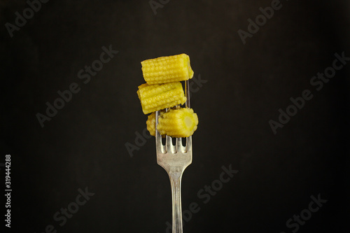 baby corn on a fork, fresh vegetables (healthy food) menu concept. food background. top view. copy space