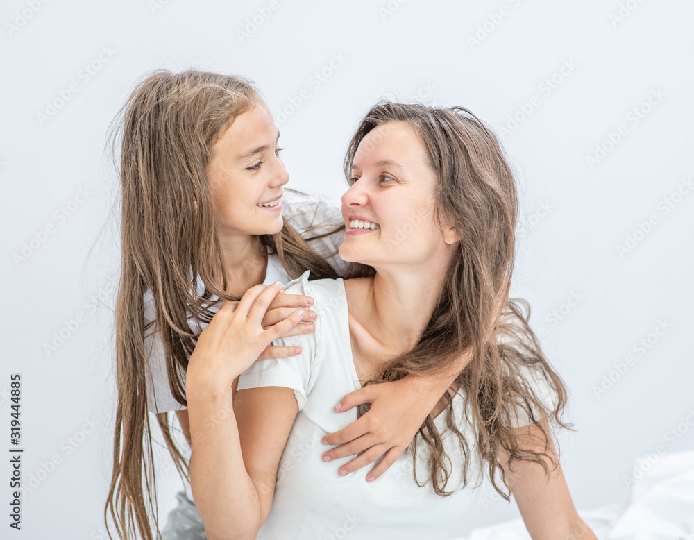 Smiling mother and her daughter have fun on the bed. Happy family concept Smiling mother and her daughter have fun on the bed. Happy family concept