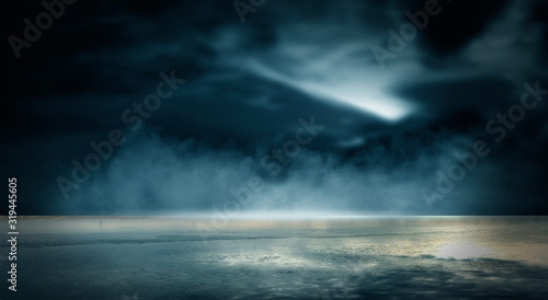 Futuristic empty night scene. Empty street scene background with abstract spotlights light. Night view of street light reflected on water. Rays through the fog. Smoke, fog, wet asphalt with reflection