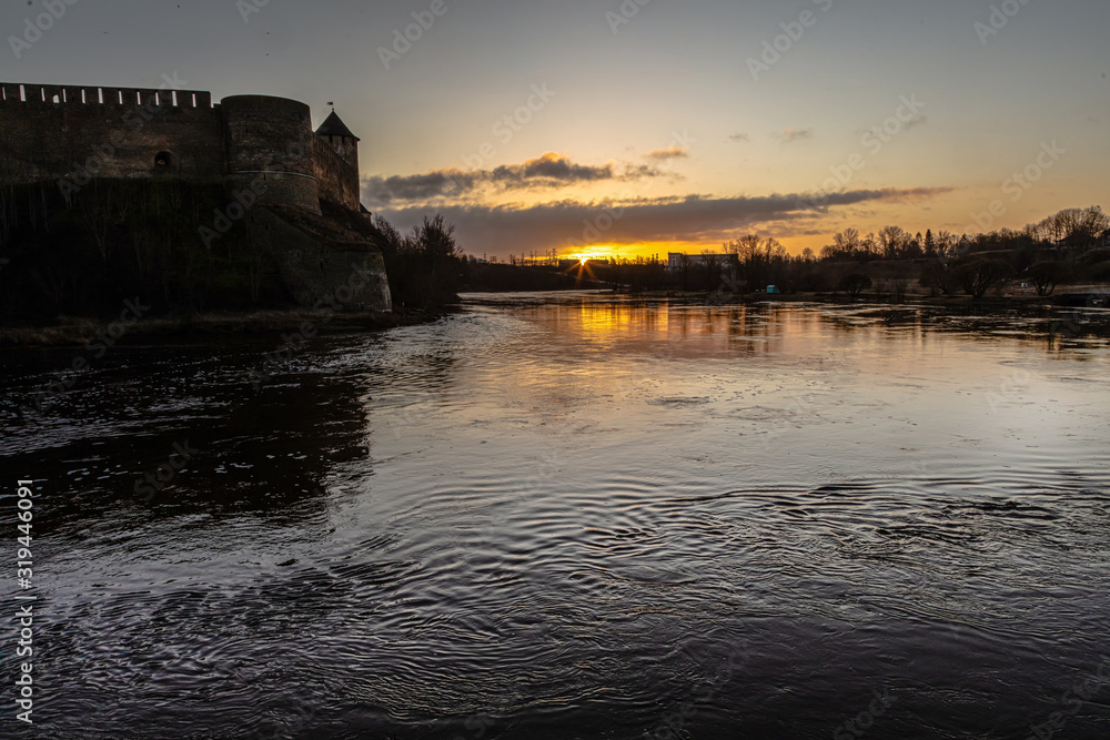 View of a medieval fortress and a river at sunrise