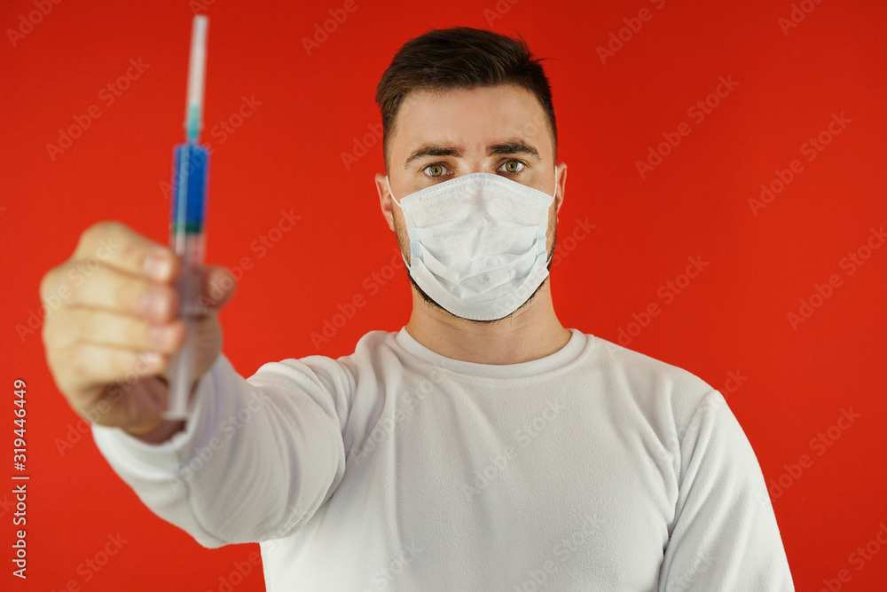 A man with a vaccine in a blue syringe. The concept of the virus. Viral vaccine A man with a vaccine in a blue syringe. The concept of the virus. Viral vaccine