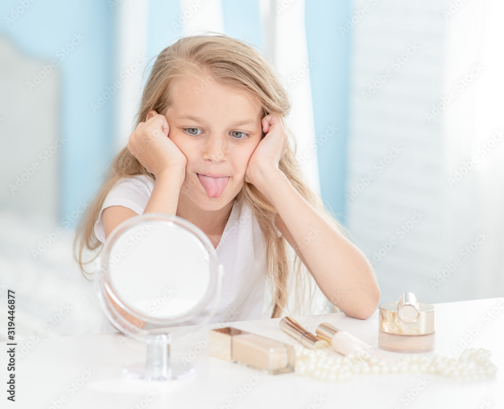 Sad girl grimaces while looking in the mirror at home Sad girl grimaces while looking in the mirror at home