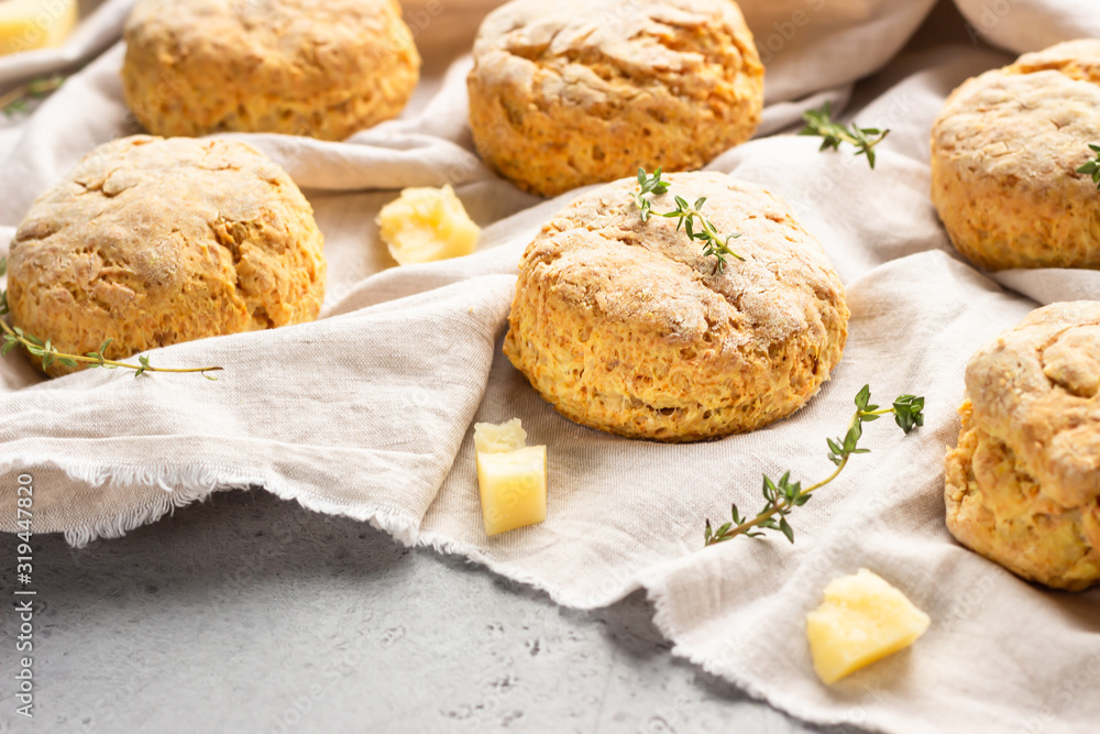 Cheese scones, pieces of cheese and thyme on a grey napkin. Grey stone background, toned image.