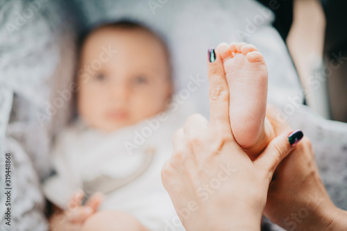 Mother holding little baby boy feet in hands. Newborn concept