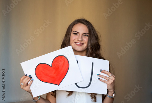 Принти на полотні Beautiful smiling brunette woman holding two white cards with i love you words and red heart