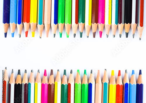 Two rows of different colored wax crayons arranged facing each other on a white background