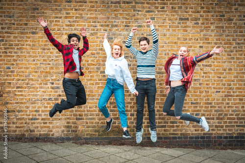 Happy teen friends jumping in front of a wall