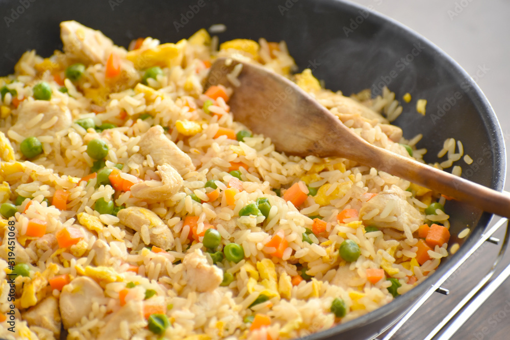 Chicken and egg fried rice with green peas and carrot in a frying pan. Chicken and egg fried rice with green peas and carrot in a frying pan.