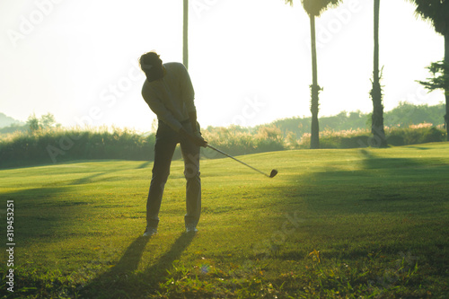 Golfer putting golf ball on the green golf, lens flare on sun set evening time.