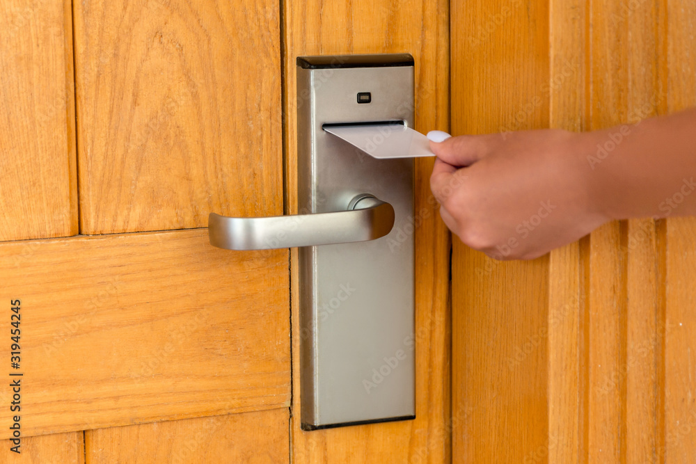 Female hand putting and holding magnetic key card switch in to open hotel room door Female hand putting and holding magnetic key card switch in to open hotel room door