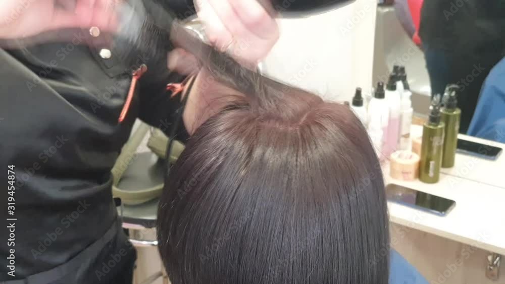 The master is engaged in painting and tinting. Drying the client with dark, wet hair dryer. Hairstyle. The master is engaged in painting and tinting. Drying the client with dark, wet hair dryer. Hairstyle.