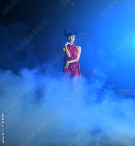 beautiful girl in clothes of the goddess of the earth in the rain in smoke on a black background
