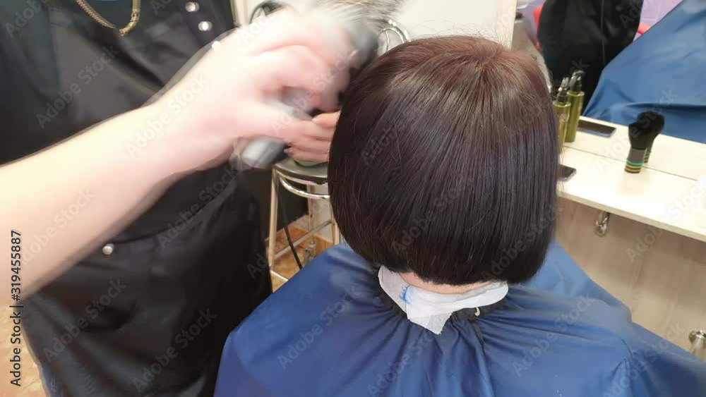 The master is engaged in painting and tinting. Drying the client with dark, wet hair dryer. Hairstyle. The master is engaged in painting and tinting. Drying the client with dark, wet hair dryer. Hairstyle.