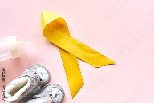Fototapeta Naklejka Na Ścianę i Meble -  Childhood Cancer Awareness Golden Ribbon and stethoscope on yellow background. Childhood Cancer Day February, 15.  W