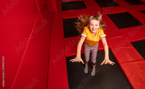 Happy little girl having fun while jumping on trampoline