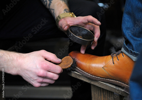 Shoeshiner hands polishing client boots with boot brush and blacking