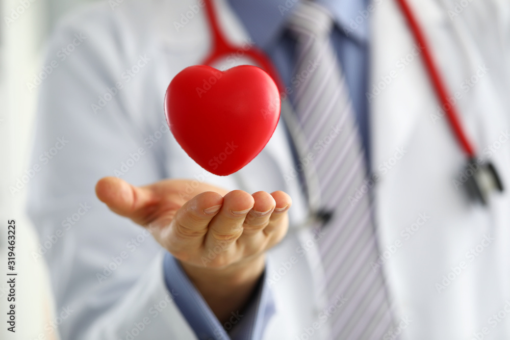 Male medicine doctor hands holding and covering red toy heart - obrazy, fototapety, plakaty 