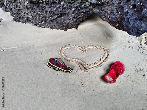 A heart drawn in the sand andflip flops of a couple. Symbol of love.