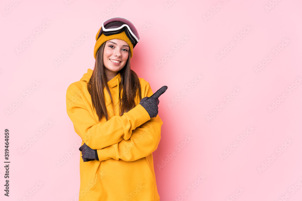 Young caucasian skier woman isolated smiling and pointing aside, showing something at blank space. Young caucasian skier woman isolated smiling and pointing aside, showing something at blank space.