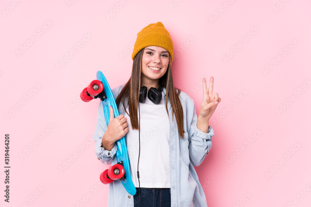 Young skater woman holding a skate showing number two with fingers. Young skater woman holding a skate showing number two with fingers.