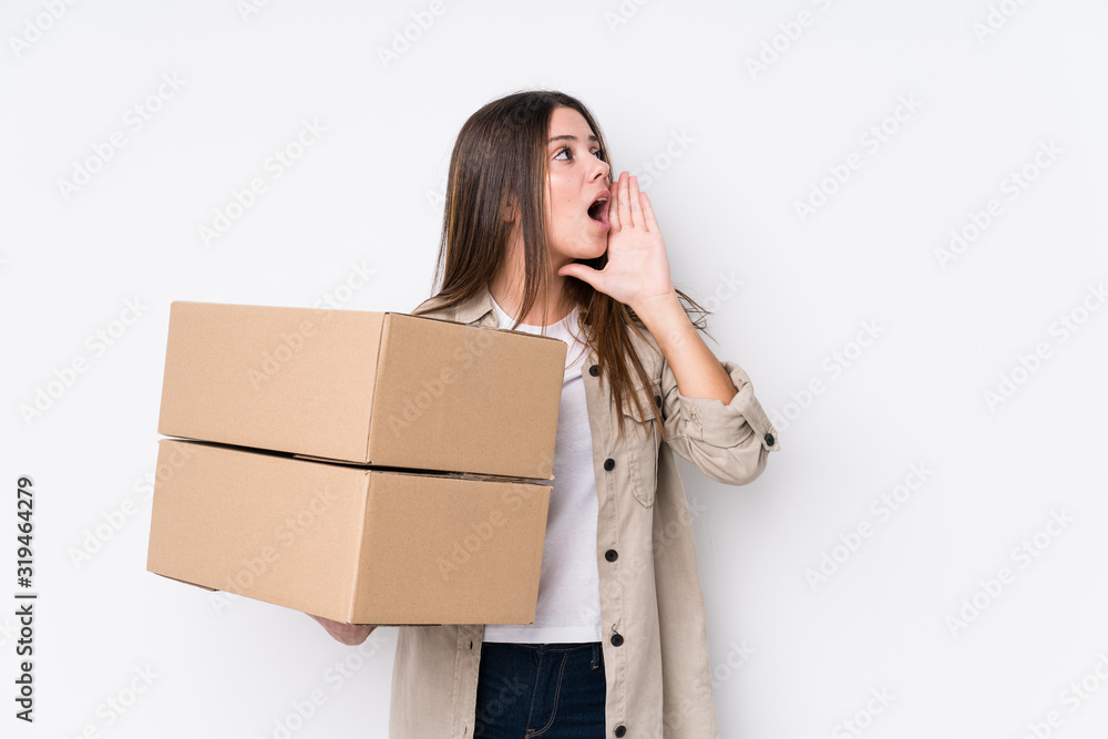Young caucasian woman moving to a new home shouting and holding palm near opened mouth. Young caucasian woman moving to a new home shouting and holding palm near opened mouth.