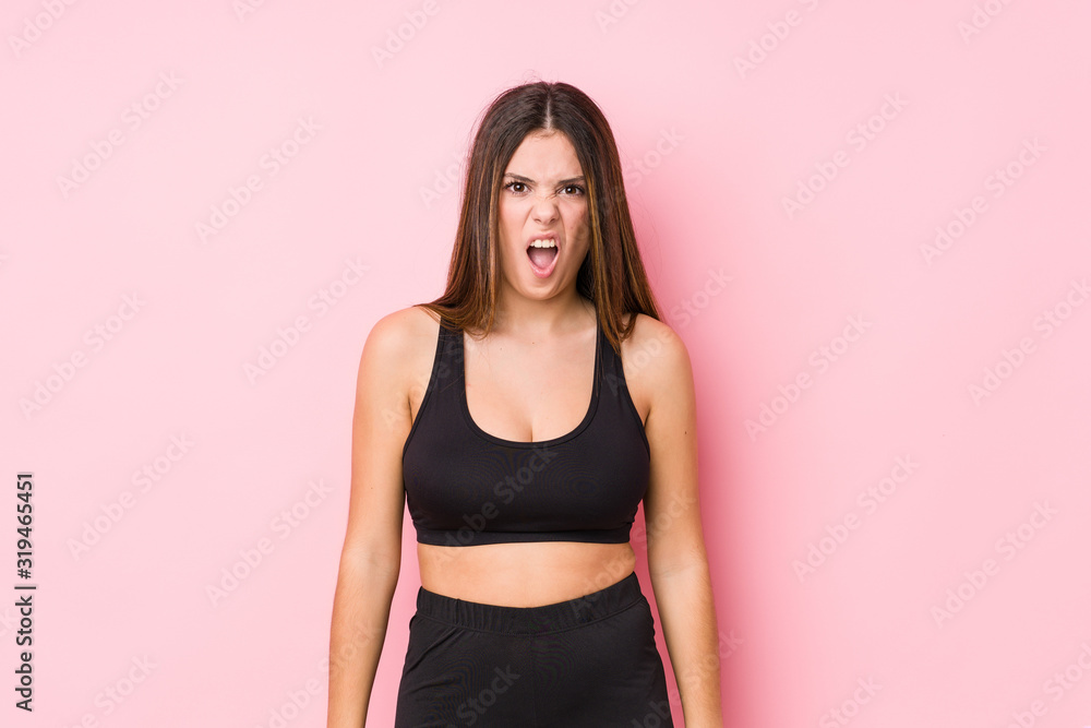 Young fitness caucasian woman isolated screaming very angry and aggressive. Young fitness caucasian woman isolated screaming very angry and aggressive.