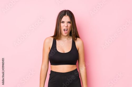 Young fitness caucasian woman isolated screaming very angry and aggressive.