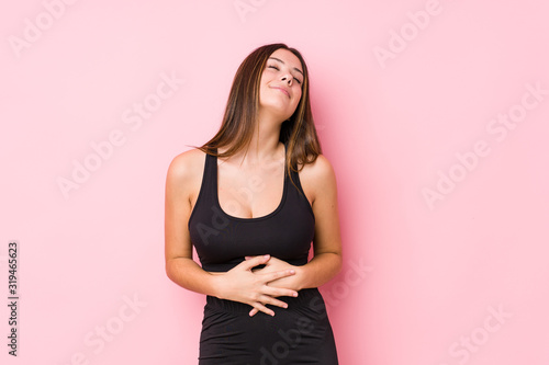 Young fitness caucasian woman isolated touches tummy  smiles gently  eating and satisfaction concept.