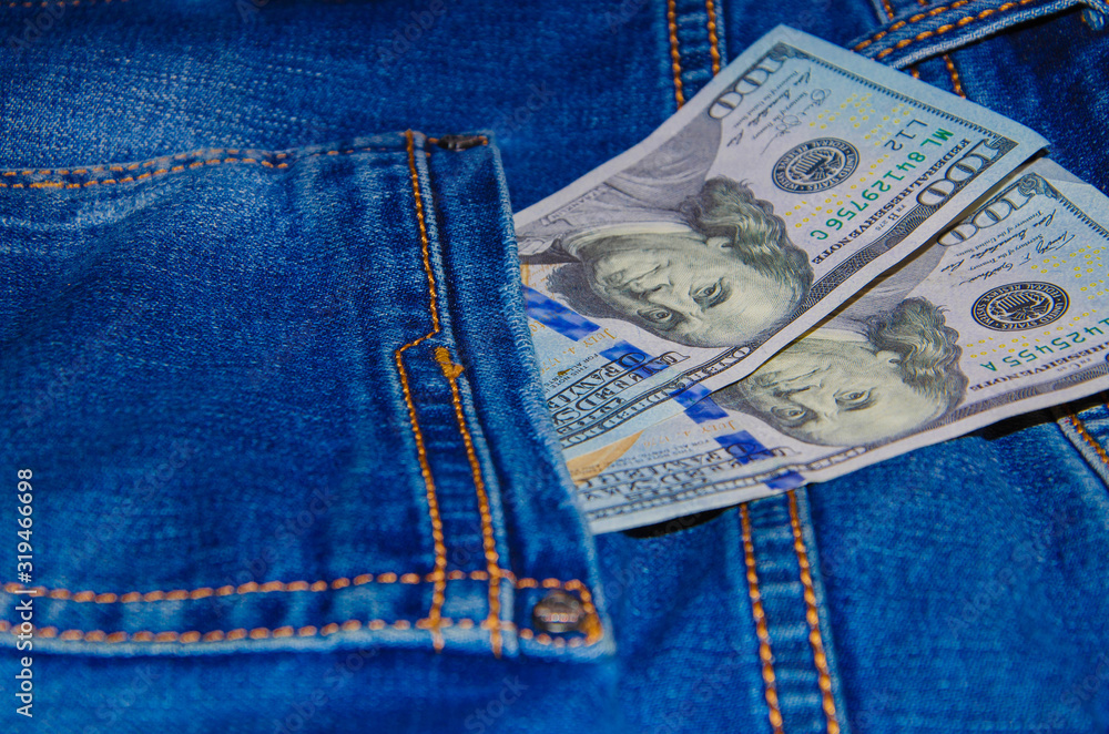 American banknotes in jeans pocket. A note in denominations of $ 100 peeps, stick out from the back, the foremost pants pocket. Money falls out of pocket. Flare effect. View from different angles American banknotes in jeans pocket. A note in denominations of $ 100 peeps, stick out from the back, the foremost pants pocket. Money falls out of pocket. Flare effect. View from different angles