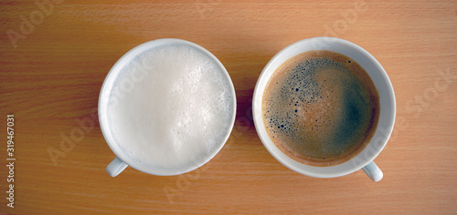 a cup of hot milk and a cup of espresso on wooden table