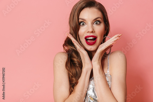 Woman in bright sequins dress isolated over pink wall