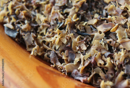 Extreme close up of a wooden bowl full of Irish Moss seaweed (Chondrus crispus). A common red algae, used as a clarifying agent for fining beer, during the home brewing process. Selective focus. photo