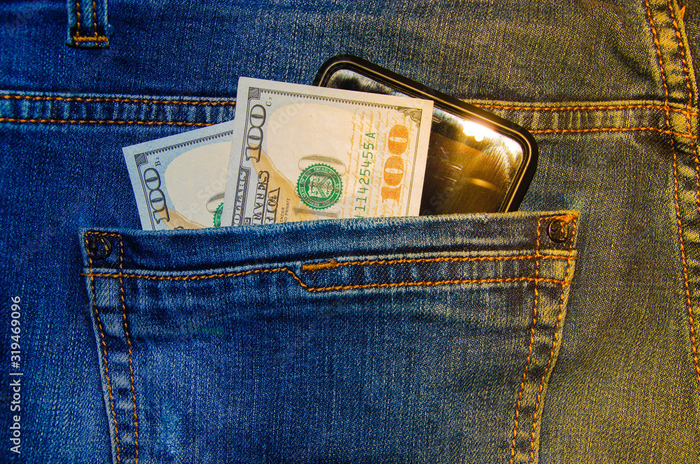 American banknotes in jeans pocket denominations of $ 100 peeps, stick out from the back, the foremost pants pocket. Money falls out of pocket. Flare effect. View from different angles American banknotes in jeans pocket denominations of $ 100 peeps, stick out from the back, the foremost pants pocket. Money falls out of pocket. Flare effect. View from different angles