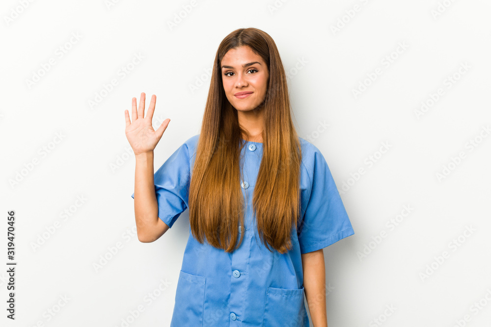 Young caucasian nurse woman smiling cheerful showing number five with fingers. Young caucasian nurse woman smiling cheerful showing number five with fingers.