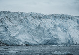 Close Up shot of huge Glacier wall. Large chunks of ice breaking off. Moody and overcast weather. Eqip Sermia Glacier called Eqi Glacier. Greenlandic ice cap melting because of global warming.