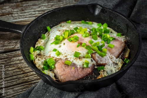 Fried eggs with ham on an old wooden background.