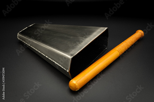 A bongo bell with stick lying on a black background photo