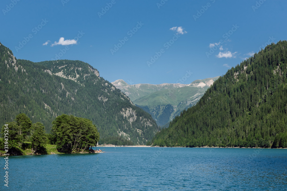 View of Swiss lake with blue waters, mountain hills with dense coniferous forests and crystal blue sky in the background, Sufnersee lake, Switzerland.