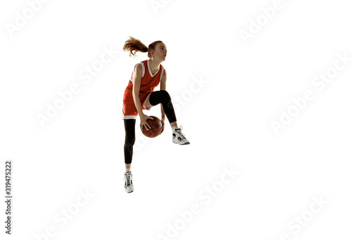 Young caucasian female basketball player in action, motion in jump isolated on white background. Redhair sportive girl. Concept of sport, movement, energy and dynamic, healthy lifestyle. Training.