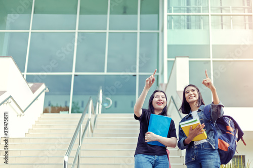 Two student Raised hands and hands point to sky at university. Education and success concept.